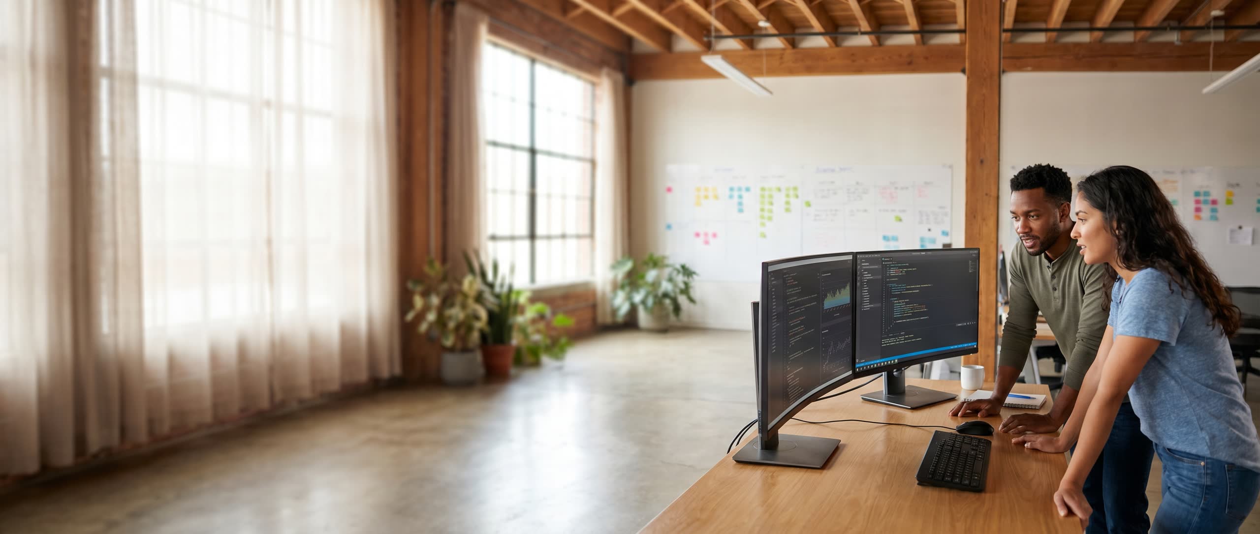 A software development team at dual monitors on the right side of the frame